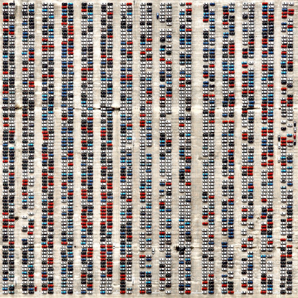 A parking lot full of cars parked in rows photographed from above